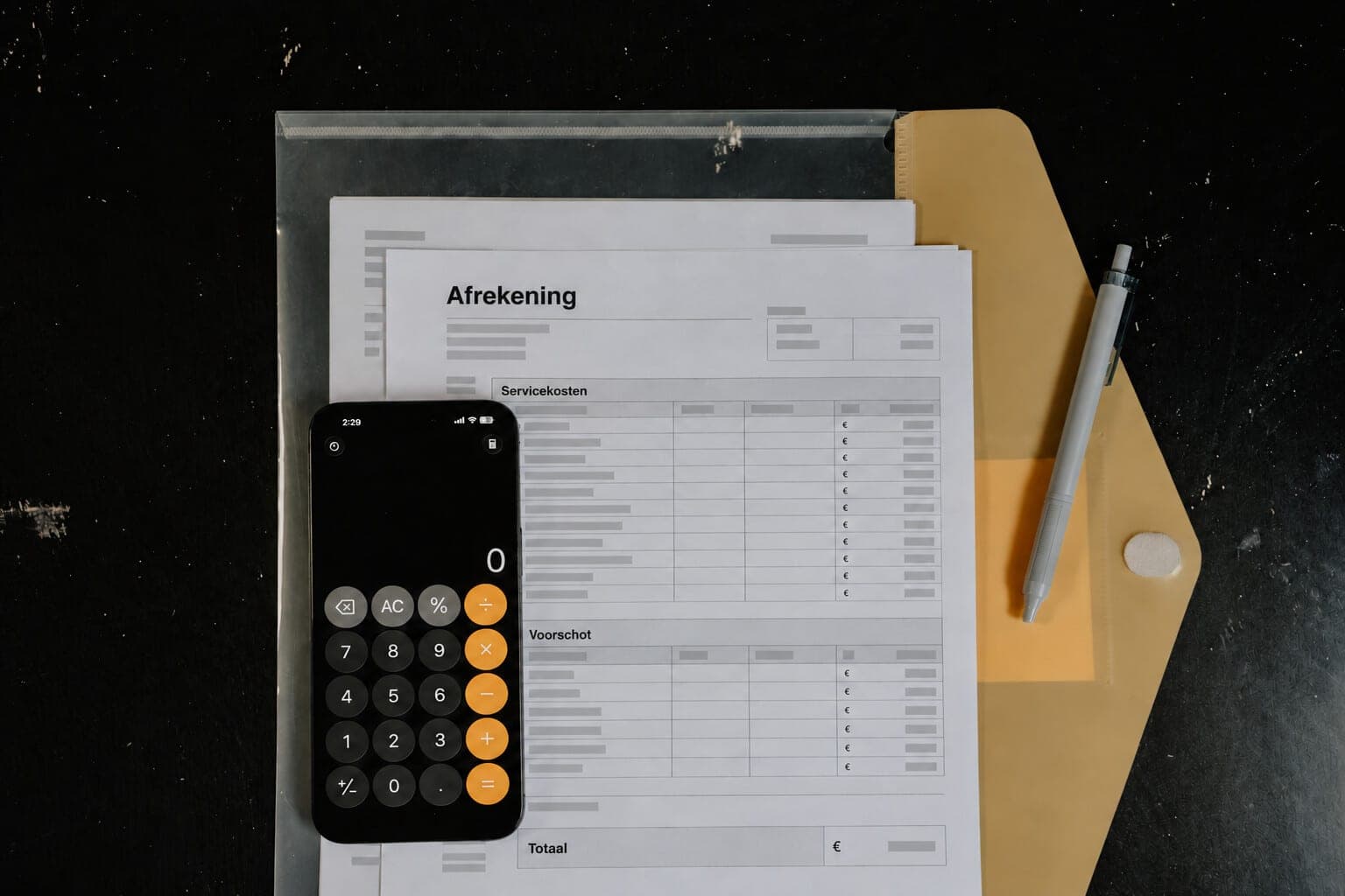 Een telefoon met de rekenmachine open ligt op een afrekening, naast de regels Servicekosten, Voorschot en Totaal.